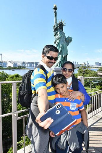 「お台場の女神像」を背景に写真を撮る観光客