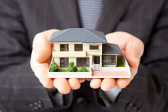 住宅模型を持つビジネスマン　不動産売却　土地売却イメージ