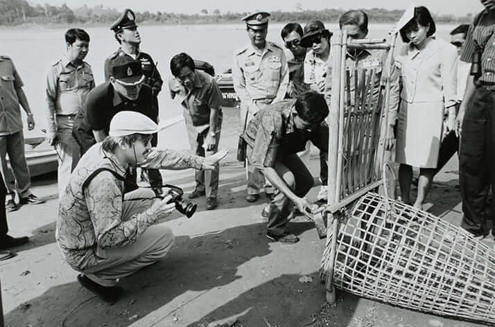 ボートを降りて、ナマズや魚を捕獲する竹細工のワナの説明を受け、カメラを構えようとされている