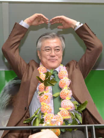 2012年、済州で遊説中、ミカンで作った花輪をもらって喜ぶ文在寅だが、ミカンはパクリ栽培の可能性が高い