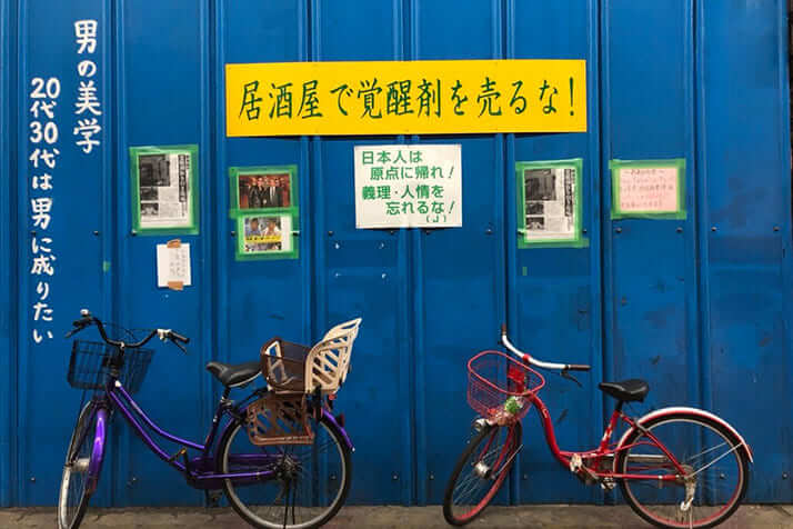 近隣の商店街の壁には「居酒屋で覚醒剤を売るな！」の看板が