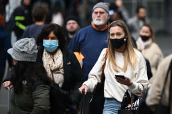 メルボルンでマスクを付けて歩く人々