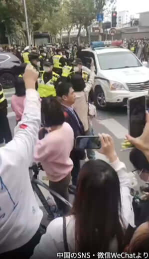 駆け付けたパトカーを追い払うデモ参加者