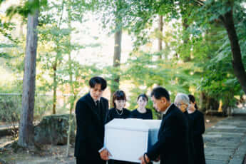 お葬式で棺桶を運ぶ遺族
