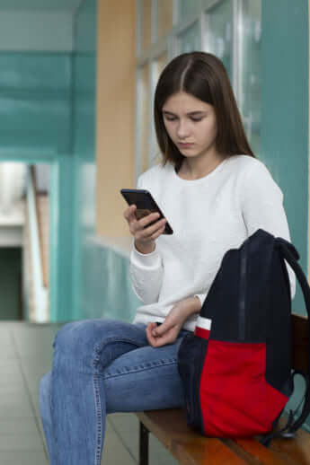 学校の廊下でスマホを見ているティーンエイジャー女の子