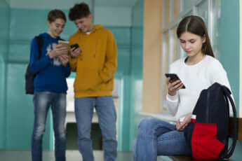 学校の廊下でスマホを見ているティーンエイジャー女の子