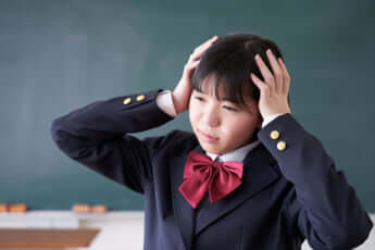 教室で頭を抱える日本人女子中学生イメージ